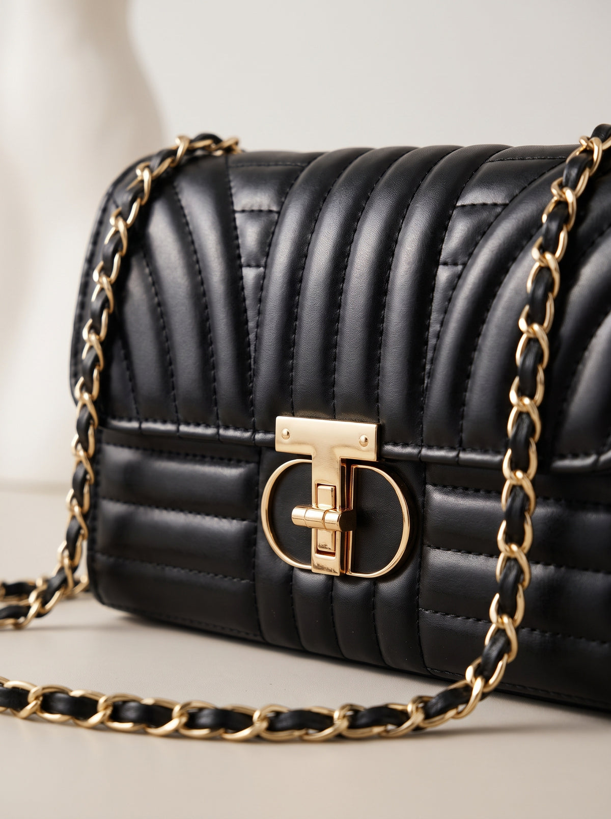Detalle del cierre dorado y la cadena del bolso acolchado negro