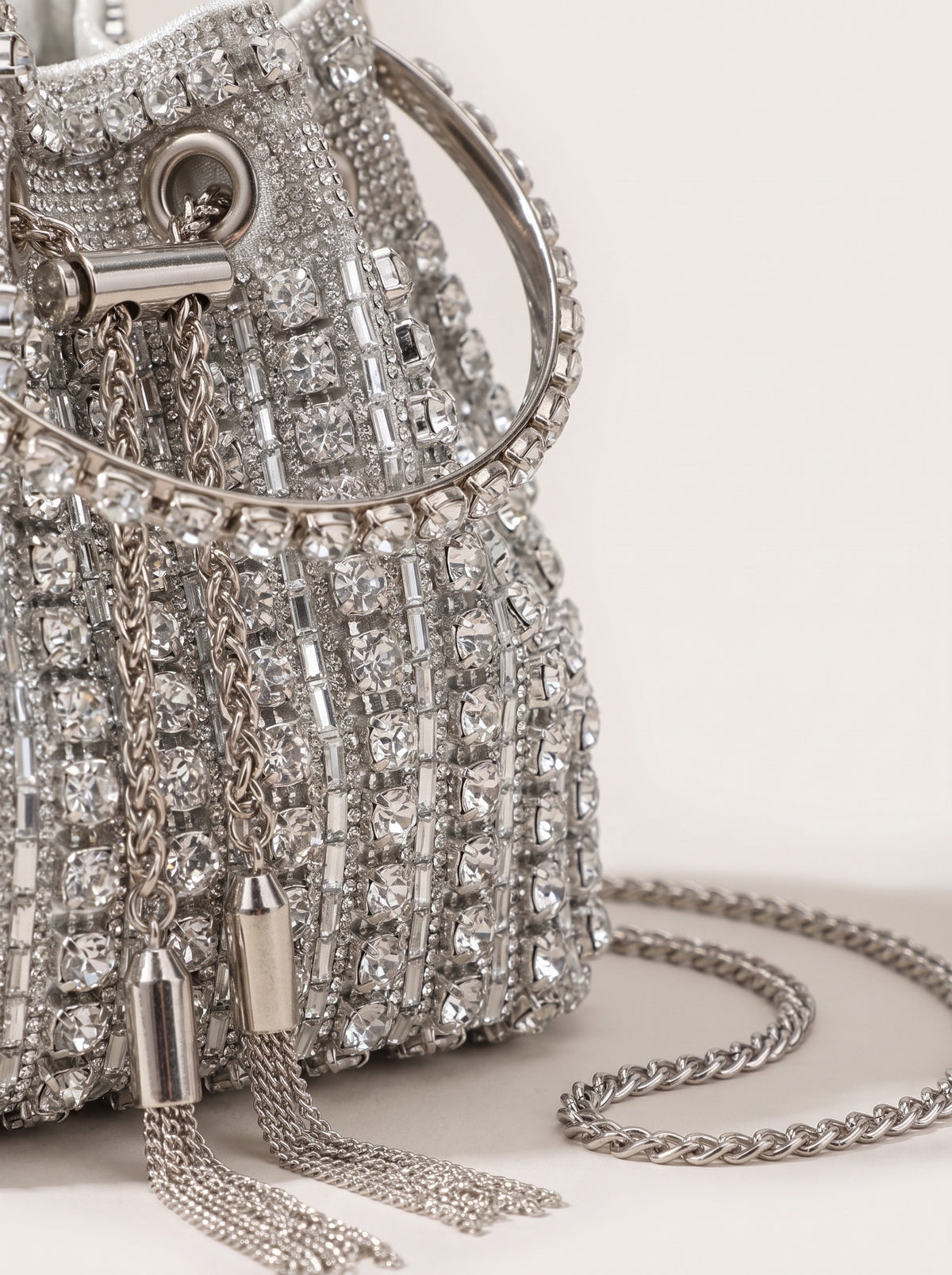 Detalle de la pedrería y el fleco del bolso saco plateado