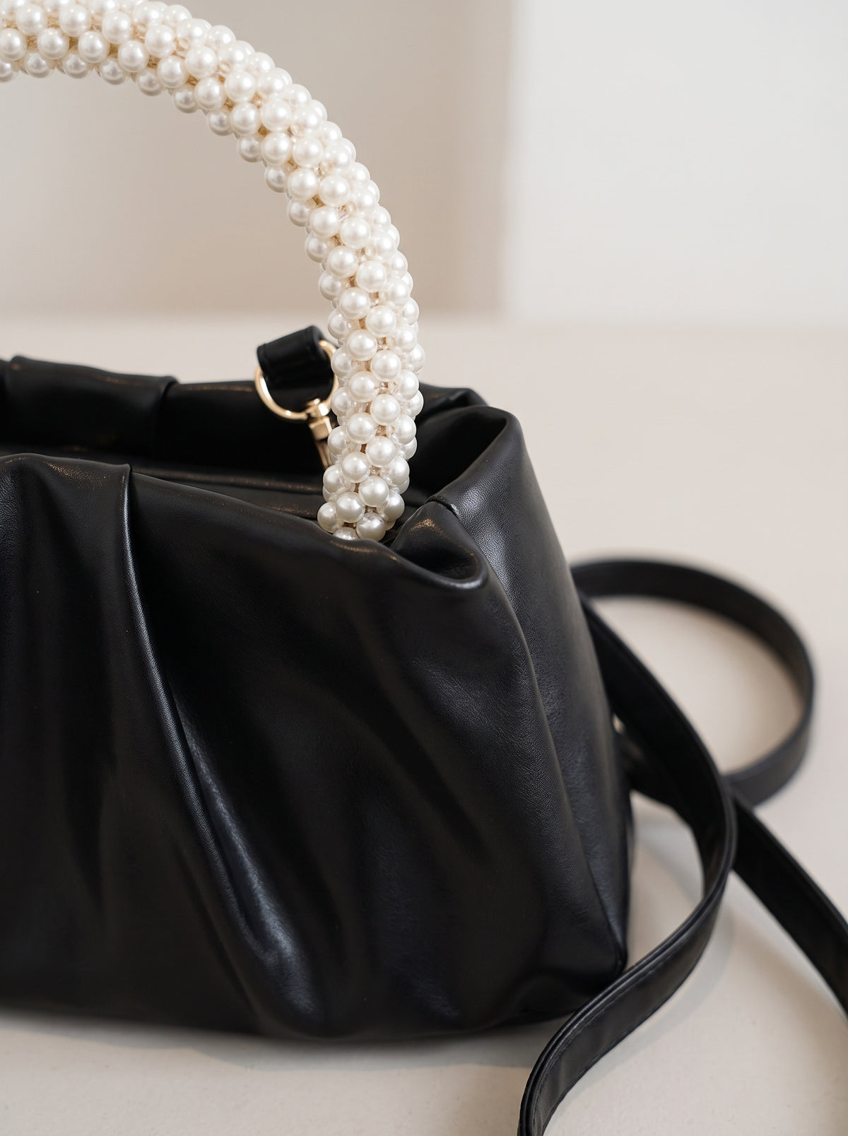 Detalle del asa de perlas del bolso fruncido negro